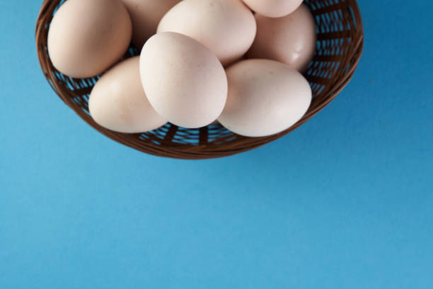 istock top view of basket of white eggs on blue background 1360207148