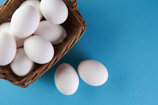 istock top view of basket of white eggs on blue background 1360207176