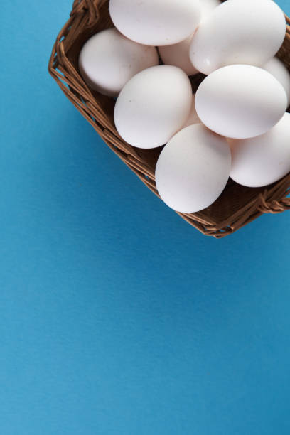 istock top view of basket of white eggs on blue background 1360207177