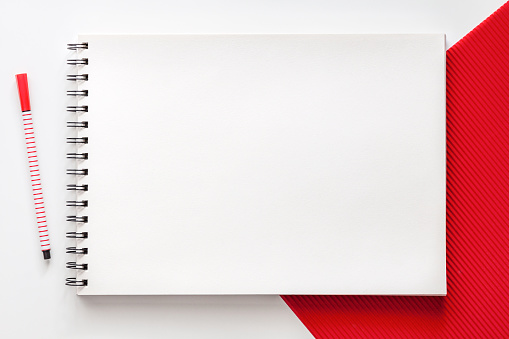 White school creative desk with red elements. Space for text. Mockup sketchbooks. Real photo, top view. School accessories. Minimal composition