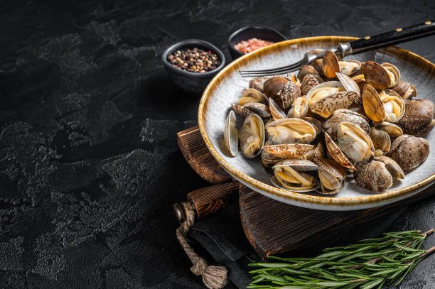 istock Steamed cooked shells Clams vongole in a plate with herbs. Black background. Top view. Copy space 1360209361