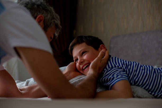 istock A smiling boy and his dad are on the bed. A young boy is lying with pillows under his head. They are playing, rolling over on the bed, and smiling. 1360211022