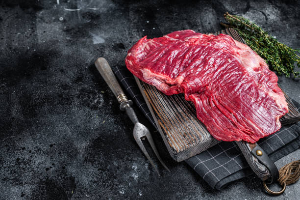 istock Uncooked Raw Flank or flap beef steak on butcher board. Black background. Top view. Copy space 1360213222