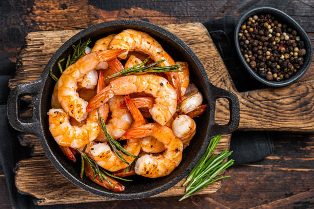 gamberi arrosti gamberetti in padella con erbe e aglio. sfondo in legno scuro. vista dall'alto - grilled shrimp foto e immagini stock