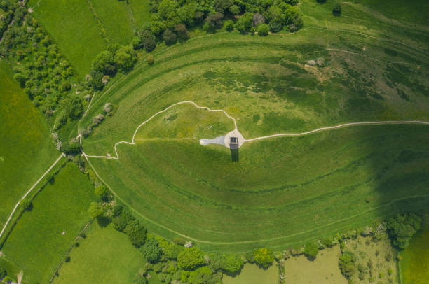 glastonbury tor von drohne an sonnigen tagen gefilmt, ikonisches denkmal mitten in der landschaft - st michaels church stock-fotos und bilder