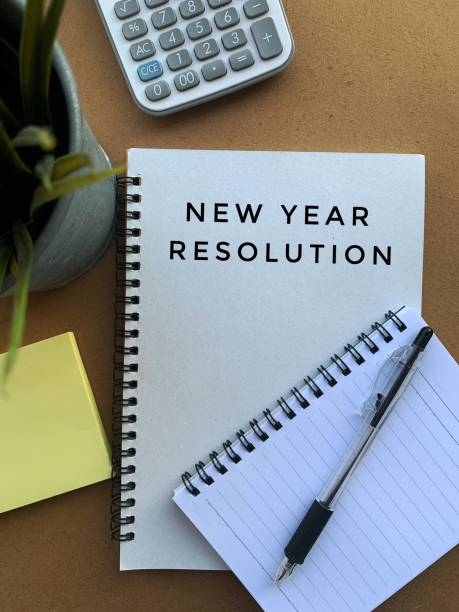istock New year resolution text on note pad with pen, calculator, plant, sticky note and brown table background 1360215031