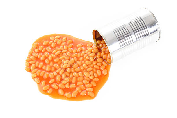 Spilled tin of baked beans on a white background