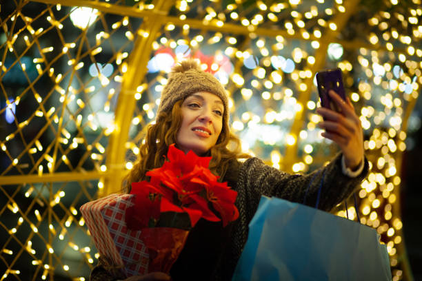 istock Woman Holding Christmas present and using phone 1360217304