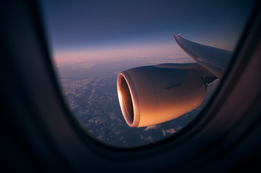 View from window of airplane during night flight above ocean. Selective focus on jet engine.\