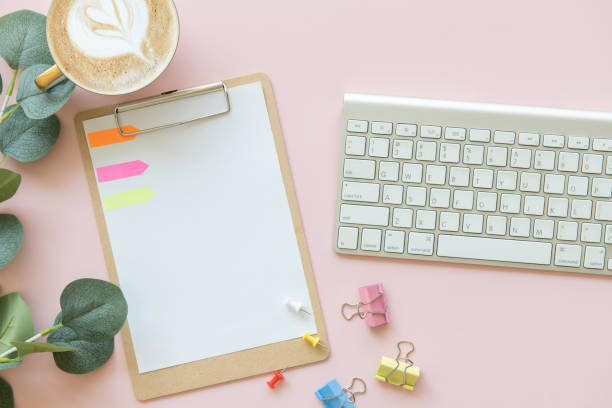 istock pink office desk table with blank paper mockup, Paper clip, Clipboard, Eucalyptus leaf, post-it. Top view with copy space, flat lay. Pastel. 1360219324