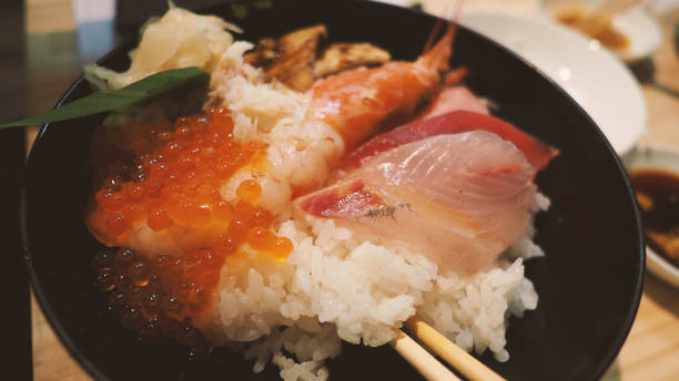 imágenes de cerca de un tazón de arroz de mariscos japoneses o kaisendon sashimi donburi o kaisen chirashi don que tienen cangrejo de camarones fresco ogura uni crudo y pescado en un tazón de arroz. mesa de madera desde el ángulo de visión superior. - chirashizushi fotografías e imágenes de stock