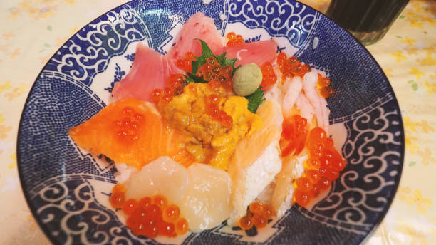 Close up images of japanese seafood rice bowl or kaisendon sashimi donburi or KAISEN CHIRASHI DON which have raw fresh ogura uni shrimp crab and fish on rice bowl. wood table from top view angle. imágenes de cerca de un tazón de arroz de mariscos japoneses o kaisendon sashimi donburi o kaisen chirashi don que tienen cangrejo de camarones fresco ogura uni crudo y pescado en un tazón de arroz. mesa de madera desde el ángulo de visión superior.