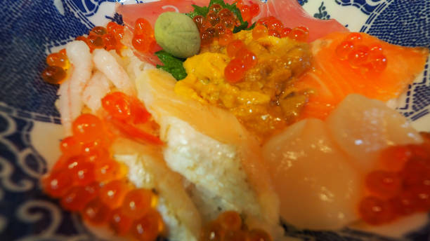 Close up images of japanese seafood rice bowl or kaisendon sashimi donburi or KAISEN CHIRASHI DON which have raw fresh ogura uni shrimp crab and fish on rice bowl. wood table from top view angle. imágenes de cerca de un tazón de arroz de mariscos japoneses o kaisendon sashimi donburi o kaisen chirashi don que tienen cangrejo de camarones fresco ogura uni crudo y pescado en un tazón de arroz. mesa de madera desde el ángulo de visión superior.