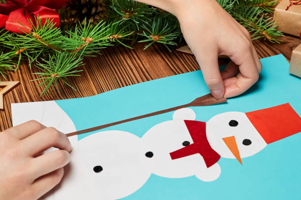 istock A girl makes a Christmas greeting card from colored paper 1360222023