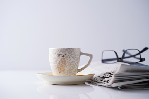 tea cup with saucer and newspaper with eyeglasses