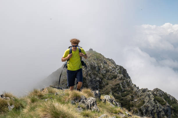 istock Young man hikes along grassy mountain ridge 1360224615