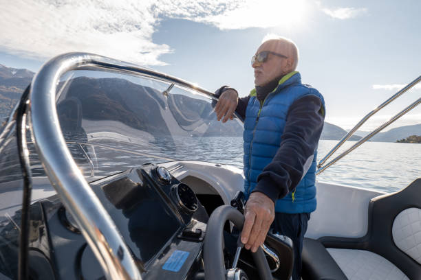istock Mature man pilots boat on calm lake waters 1360225948