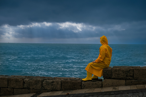 Lonely young man with yellow raincoat  ,bad weather conditions,waves.Storm and clouds