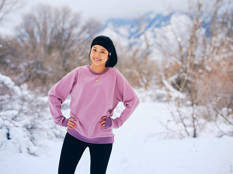 A woman stretching in an outdoor winter location, before exercising.