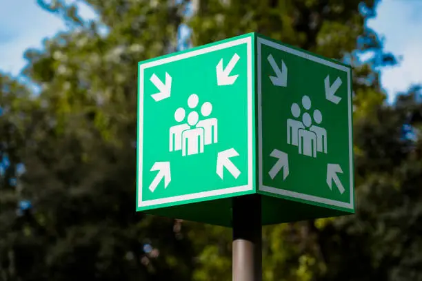 Close up of an outdoor sign indicating where people should assemble following an emergency building evactuation for a fire alarm or similar event.