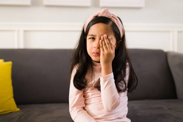 Sad elementary girl with conjunctivitis