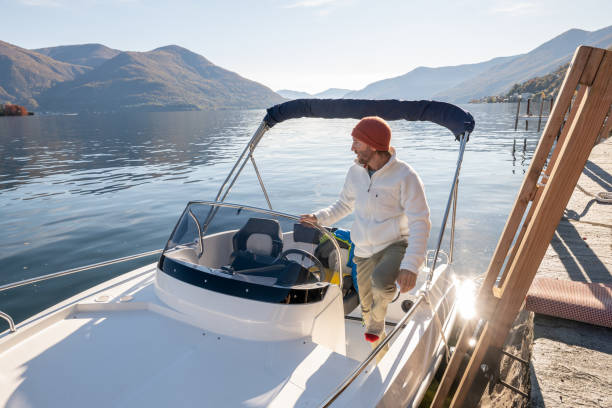 istock Young man on boat on lake in Autumn 1360232468