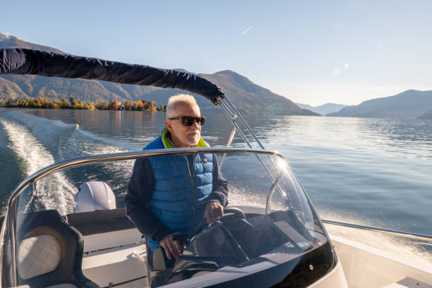 istock Mature man piloting boat on lake in Autumn 1360232877