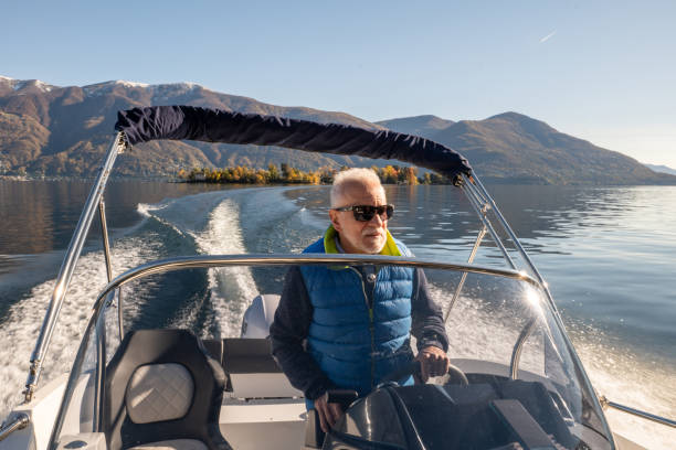 istock Mature man piloting boat on lake in Autumn 1360233334