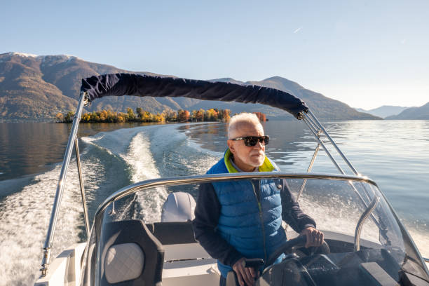 istock Mature man piloting boat on lake in Autumn 1360233421