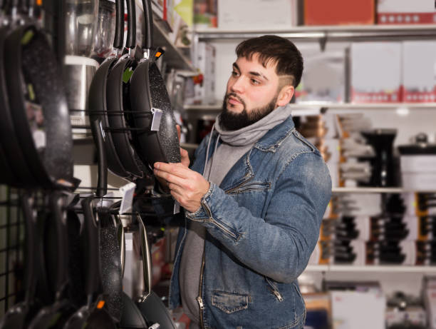 istock Bearded man chooses frying pans for his kitchen 1360238948