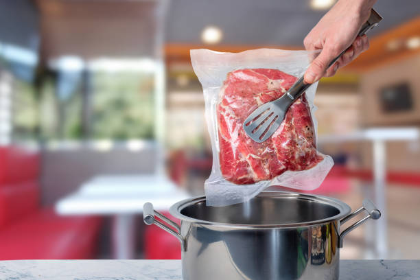 cook met la viande emballée sous vide pour une cuisson à basse température dans une casserole. - airtight food box package photos et images de collection