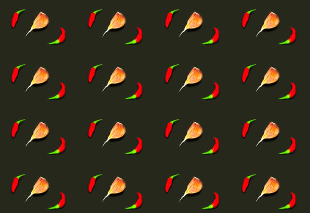 Pattern of red chili peppers and garlic on dark background. Creative layout for design. Close-up
