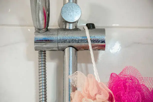 Photo of Dirty chrome shower rod with limescale that should be cleaned.