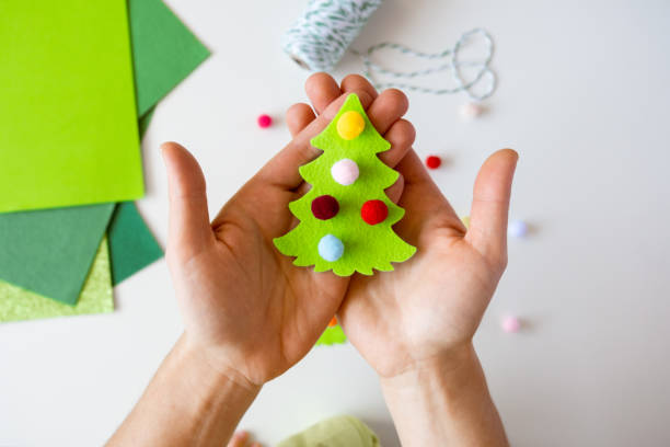 istock making Christmas decorations on white desktop. Overhead shot. Flat lay. Christmas tree made of cloth 1360246007