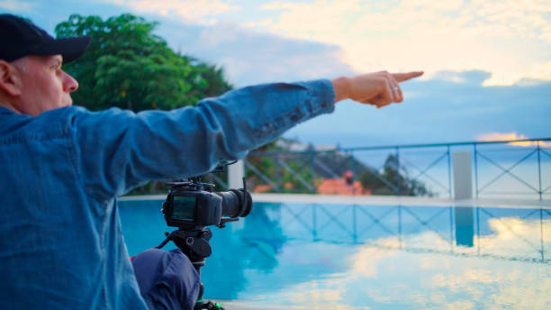 istock Infinity pool on a patio. Man with suitcase posing for a photo. Photographer giving tips 1360246817