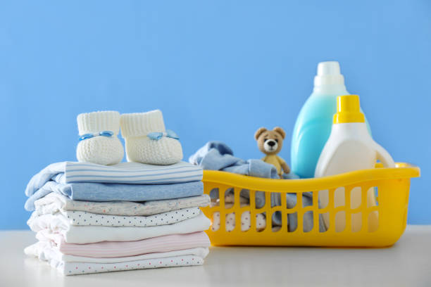 istock Detergents and children's clothes on white table near blue wall 1360247208