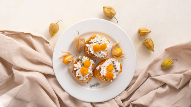 Ricotta Crostini with Physalis fruits on a white plate stock photo