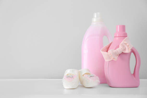 istock Bottles of detergent and children's clothes on white table. Space for text 1360249166