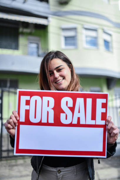 istock Smiling Female Putting House For Sale 1360249952