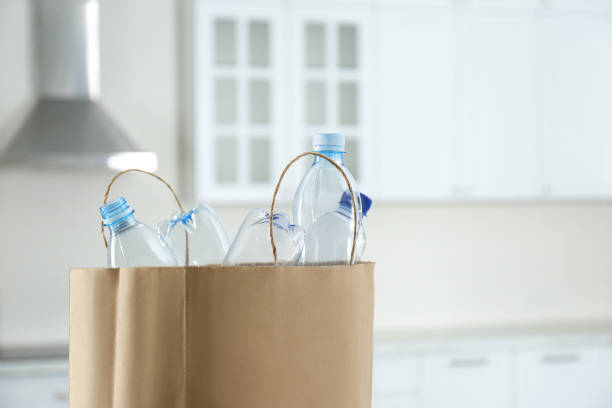 istock Paper bag with used plastic bottles in kitchen, space for text. Recycling problem 1360252743