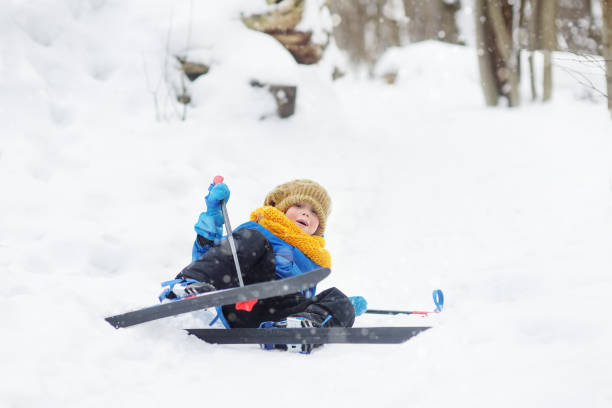 Cute little boy is learning ski during walk in the winter forest. Outdoor activities for children in winter. Kids equipment for winter sports. stock photo