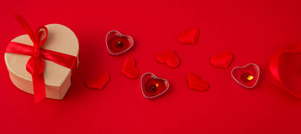 istock Saint Valentine top view composition with gift box, candles, hearts on red background 1360256715