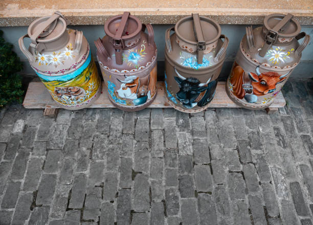 A Collection of Traditional Metal Milk Pails Sit on a Wooden Structure in a Scenic Mountainous Landscape. This Image Evokes the Heritage of Dairy Farming and Cheese Production in a Rural Highland Setting