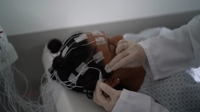 Doctor removing electrodes of patient's head after polysomnography (sleep study)