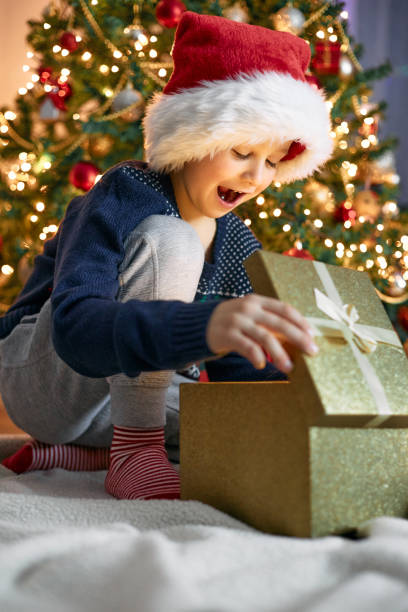 istock A cute boy opens a gift near the New Year tree. Christmas miracle 1360264690