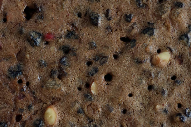 istock Full frame image surface view of homemade, Christmas fruitcake, chopped nuts, dried fruit (raisins, currants and sultanas) and glace cherry pieces, elevated view 1360266076