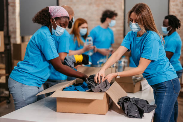 istock Volunteers packing food and clothes in donation boxes 1360267191