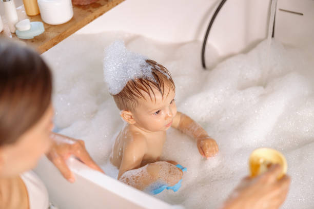 istock Young mom bathing her kid in large tub. 1360268364