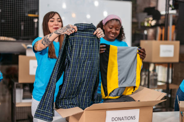 istock Volunteers in donation center folding and packing clothes in boxes 1360269288