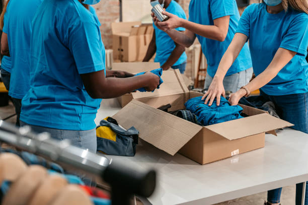 istock Volunteers in donation center folding and packing clothes in boxes 1360269307